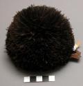Sheath, blck feather pom-pom attached to cylindrical & perforated hide sheath