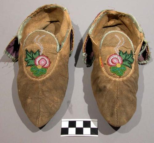 1 pair of woman's moccasins. Floral motif beading and light blue ribbon binding