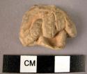 Figurine fragment; clay; torso holding cymbals.