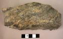 Thick, heavy, elongated quartzite fist axe or celt, with cutting edge broken off