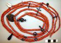 Necklace of imitation coral beads with silver coins and various other objects of