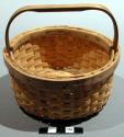 Miniature potato basket. Plain weave; circular shape with open top; wood handle.