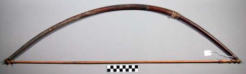 Wooden bow, one end wrapped in hide, other end split, wrapped in small piece of