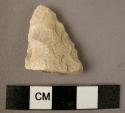 Chipped stone projectile point fragment, triangular pointed tip, white