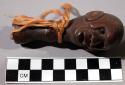 Staff finial, carved wood human head, black and red seed eyes, fiber cord at nec