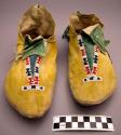 Pair of yellow painted leather moccasins with green fringe and bead *