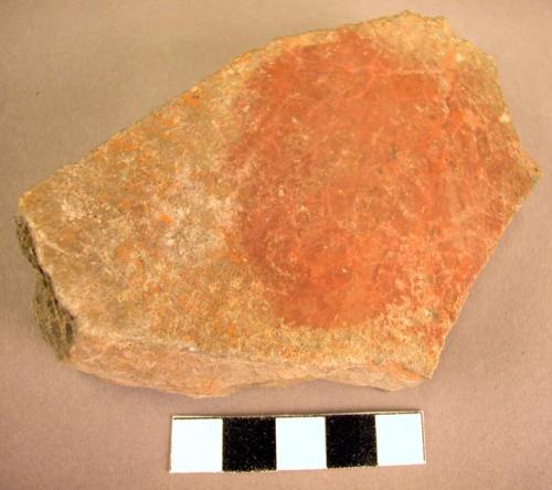 Stone palette with red paint on it