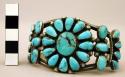 Silver cuff bracelet with inlaid turquoise, central flower design