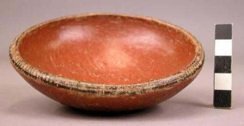 Small red pottery bowl, rim decorated in black and white