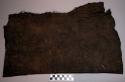 Bark cloth, black, pounded texture, semi- rectangular, folded, worn edges