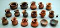 Set of miniature ceramic vessels, mostly red, some are partially black.