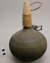 Old powder gourd, covered with knitted (?), fibre and with wooden stopper (eloma