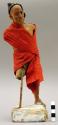 Figurine of man wearing red garment and head wrap, arms missing, legs broken