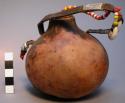 Gourd container, wood plug attached to leather carrying strap by bead decorated
