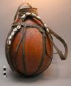 Gourd container, leather carrying strap decorated with cowrie shells.  Height ap