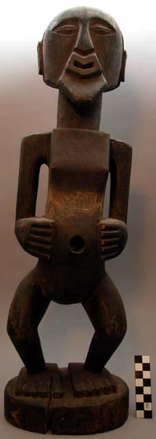 Black stained wooden carving of a standing human figure