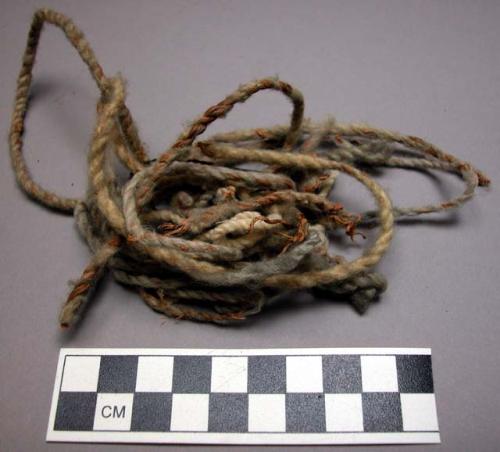 Wool string, twisted w/ some veg. fiber, 1 strand braided hair (?)