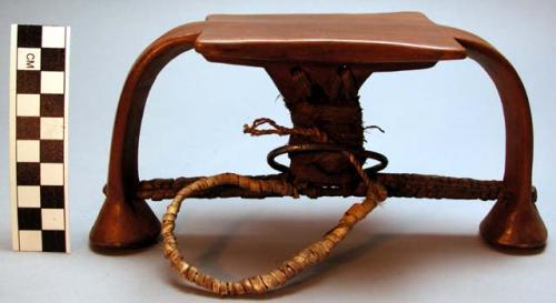 Wood headrest, rectangular platform, arched legs, hide/fabric wrap, metal ring