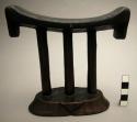 Headrest; oval base; engraved; 3 cylindrical pillars; curved rest; incised