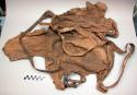 Hide object, pieces sewn together, leather straps tied roughly to object