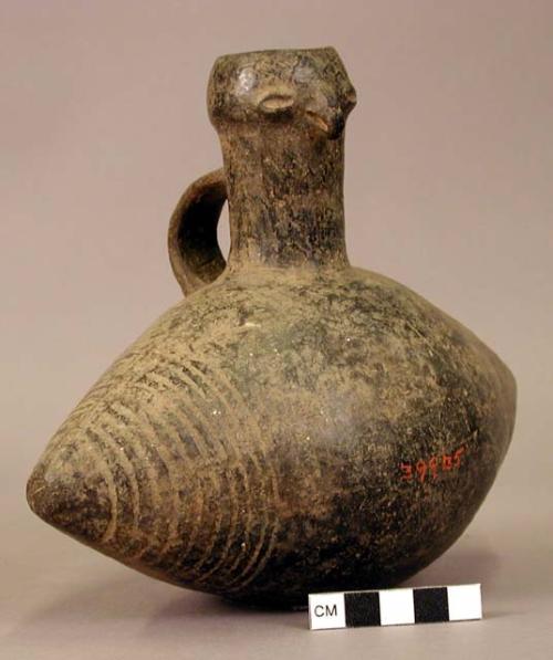 Ceramic bottle, conical shaped, incised design around ends, molded animal face a
