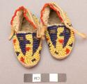 Pair of doll moccasins of skin decorated with blue, yellow and red beads