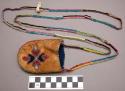 Small buckskin pouch with beadwork strap; sides stitched with red & blue cotton