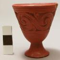 Miniature red pottery vase with base and with a scroll design