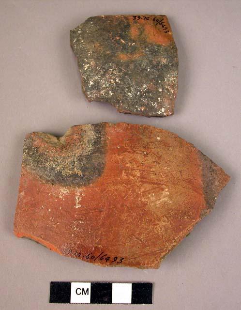 2 potsherds - mottled red and black shiny outside, dull grey inside