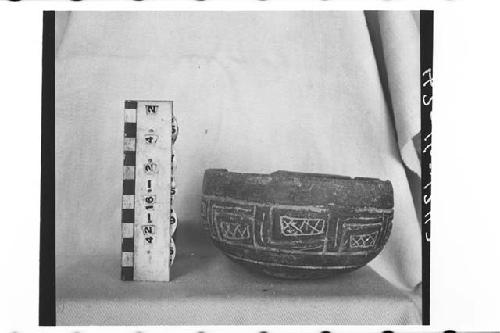 Carved pottery bowl. Shallow-round base, rounded lip. Dark brown clay.