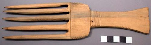 Carved wooden comb, long flared handle, 5 wide teeth, incised.