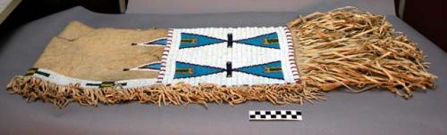 Skin saddle blanket with bead decoration and fringe.