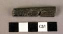 Ground stone implement, black, 2 flat edges, 2 curved sides, incised, mended