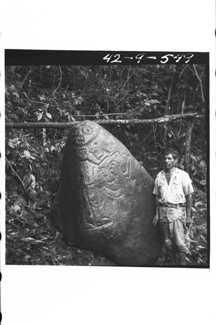 Man standing next to boulder with sculptured figure