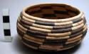 Small circular coiled basket, natural with simple black geometric design.