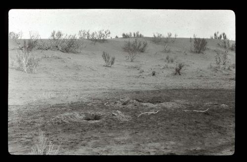 Lantern slide of desert landscape with pits in foreground