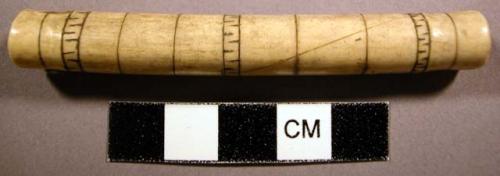 Bone needle case. Hollow tube decorated with black engravings.