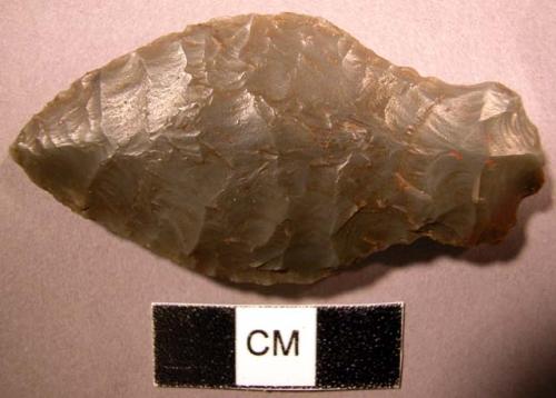 Lance head of grey flint, chipped stone. Broad head, rounded shoulder.