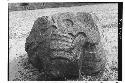 Small boulder with death's head carved in low relief. Snake issues from nose