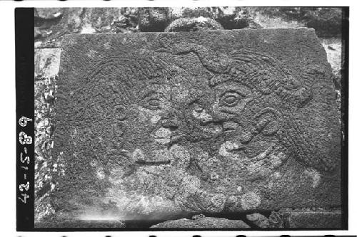 Stone slab with low relief carving of 2 heads facing each other