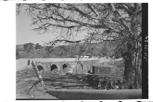 Men resting in the shade next to the old bridge