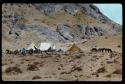 Lantern slide, closer view of encampment with looming cliff, hand-colored