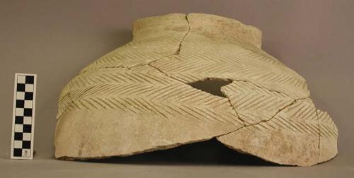 Ceramic rim sherd, mended, incised herringbone pattern, white, unslipped