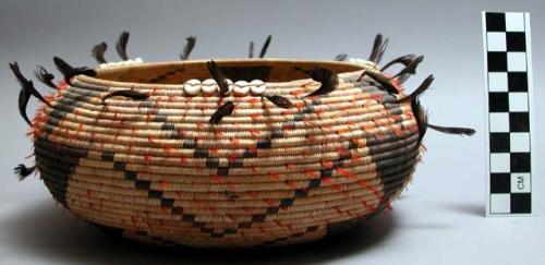 Circular coiled basket, natural with black geometric designs.