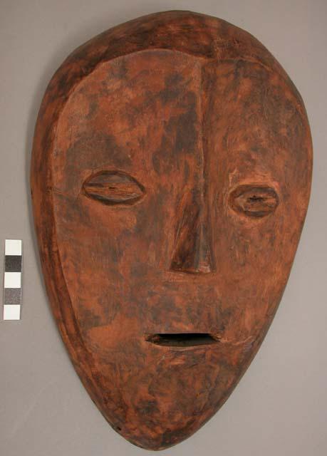 Wooden mask with slit mouth, cowrie type eyes,  pink-ochre tempera (?) applied t