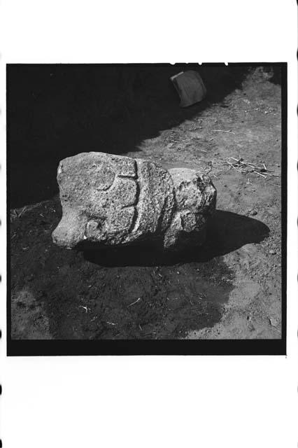 Side view of sculptured serpent head with human face in mouth