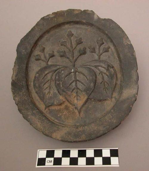 Ceramic, molded round tile, raised rim, floral designs in relief