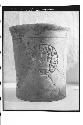 Brown cylindrical vase with carved medallions on wall.  Cat. #202.