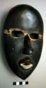 Poro society mask, with hollow eyes, and mouth,  wood, with shiny black patina a