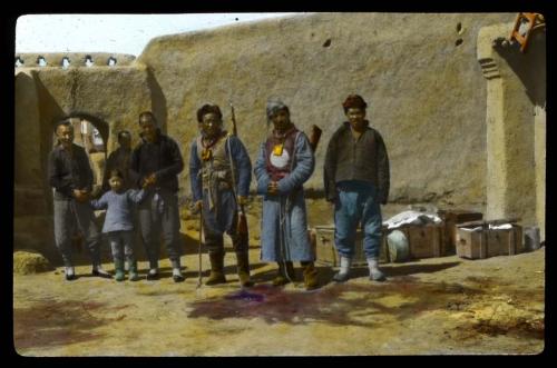 Lantern slide of men and child in front of building, hand-colored